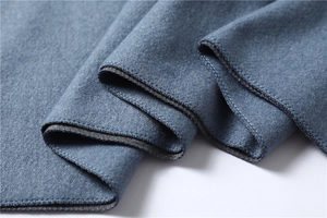 Close-up of navy blue cashmere-like scarf with detailed overlock stitching and soft texture