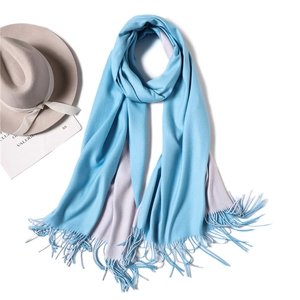 Detail of soft reversible light blue and grey cashmere-like scarf with fringe tassels