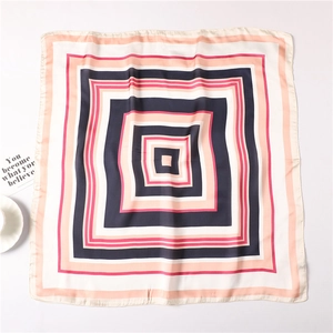 Dettaglio di foulard in seta con motivo geometrico blu navy, rosa e beige a quadrati