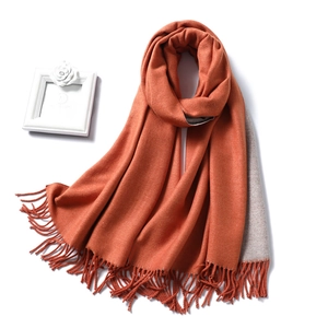 Close-up of thick double-sided winter scarf with orange and grey colors and tassels