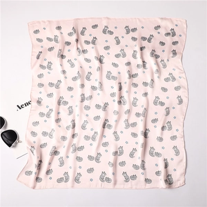 Detail of pink silk-like square scarf featuring cute fox prints and blue stars pattern