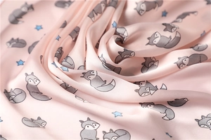 Detail of pink silk-satin scarf featuring cute cartoon fox and blue stars print patterns