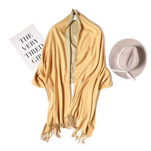 Detail of yellow and beige double-sided cashmere-like shawl with handmade fringe tassels
