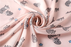 Detail of pink satin scarf showing cute fox and star prints with silky smooth texture