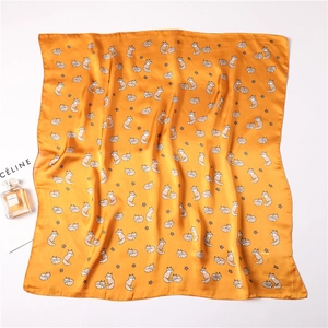 Detail of silk-like yellow square scarf with cute cartoon fox and star print pattern