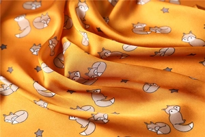 Detailed view of glossy orange silk scarf with cute cartoon fox and star prints