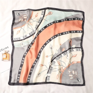 Flat lay of a multicolor square silk scarf with floral patterns and perfume bottle