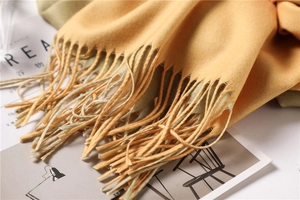 Close-up of ginger yellow cashmere-feel scarf with long fringe and soft texture
