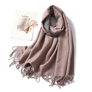 Close-up of soft cashmere-like winter scarf with fringe details and pink sunglasses