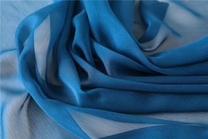 Detalle macro del chal de gasa azul pavo real con textura tejida fina y caída suave