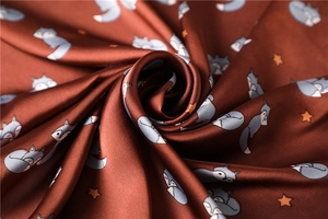 Detail showing silky satin fabric with cute fox and yellow star pattern on reddish-brown scarf
