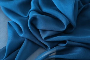 Primer plano de la textura de seda crepé azul pavo real con detalles de caída suave