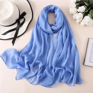 Dettaglio macro della sciarpa in seta blu reale leggera con bordi rifiniti su sfondo beige