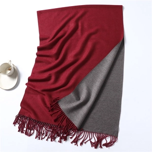 Detail of burgundy and gray double-sided scarf with twisted tassel edge on white background