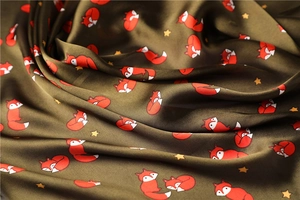Close-up of olive green satin scarf fabric with cute fox and star print details