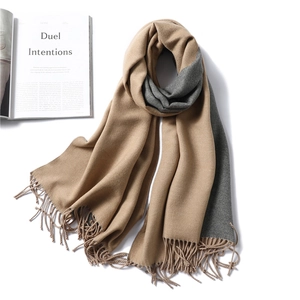 Detail of two-tone cashmere-style scarf with fringe and soft texture on white background