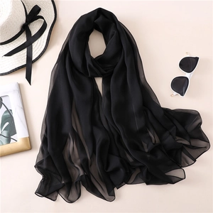 Dettaglio di una leggera sciarpa in chiffon nero con orlo piatto e trama trasparente