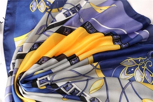 Macro shot of silk-like satin scarf featuring elegant navy blue and gold geometric patterns