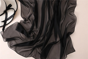 Dettaglio di elegante sciarpa in chiffon nero con trama delicata e finitura drappeggiata
