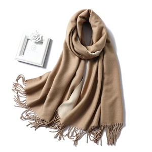 Detailed view of beige cashmere feel scarf with long tassels and thick texture