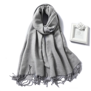 Close-up of grey knit scarf with fringe details and soft texture for winter