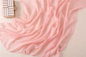 Dettaglio della sciarpa in chiffon rosa con bordi arrotolati e drappeggio morbido