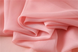 Dettaglio macro del tessuto chiffon rosa traslucido con delicata trama plissettata e caduta