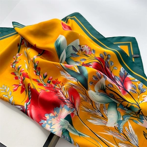 Detail of floral printed satin scarf with orange background and dark green border