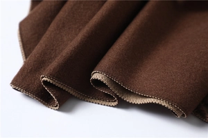 Macro shot of thick dark brown cashmere fabric showing soft texture and fine hem detail