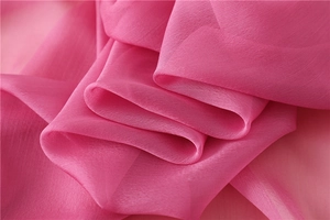 Dettaglio del leggero tessuto in chiffon fucsia con morbide pieghe e texture fine