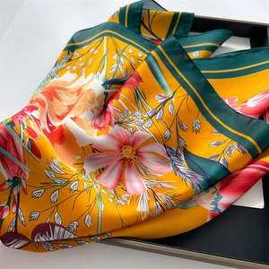 Detailed view of yellow and green silk-satin scarf with tulip floral prints in a black tray