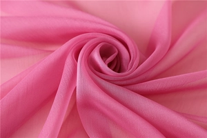 Dettaglio della sciarpa di chiffon rosa con piega a spirale e consistenza morbida e velata