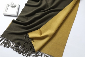 Detail of double-sided knit scarf with olive green and ginger yellow fringe tassels