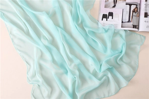 Detalle de la bufanda de gasa verde menta mostrando textura ligera y costuras de calidad
