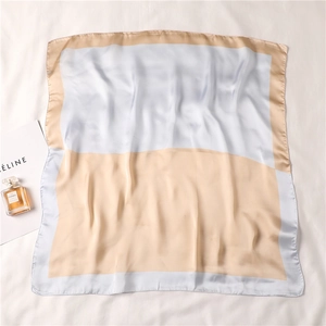 Dettaglio di un foulard quadrato in seta con blocchi di colore azzurro e oro champagne