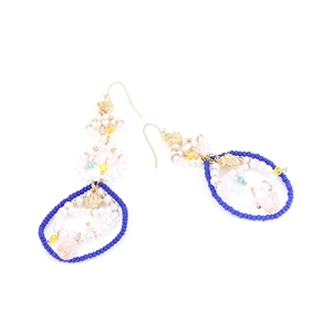Detail of bohemian drop earrings with white pearls, blue beads and golden leaf charms