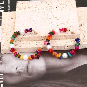 Bohemian large hoop earrings with colorful gravel stones and pearls on stone backdrop