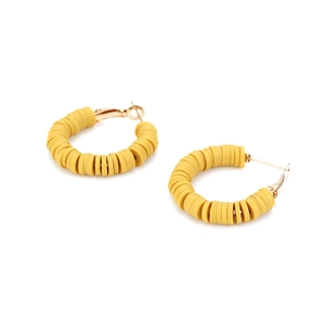 Detail view of ginger yellow polymer clay beads on gold-plated C-shaped hoop earrings