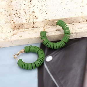 Detail of green Heishi bead hoop earrings with bohemian style on textured stone surface