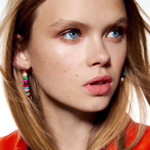 Bohemian colorful beaded hoop earrings with pearls worn by a model on white background