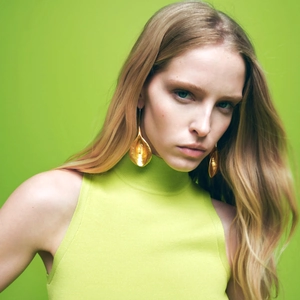 Vintage gold floral drop earrings on a model in a green sweater portrait view