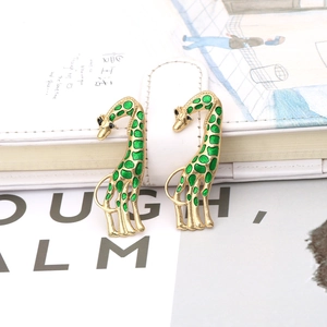 Artistic giraffe enamel earrings in gold alloy with green spots on a white notebook