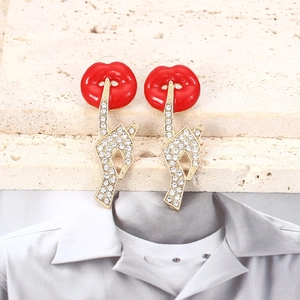 Sparkling red lips and gold gesture earrings with rhinestones on a textured stone base