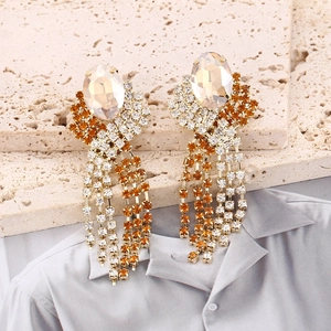Detail view of gold long tassel earrings with champagne crystal on beige stone