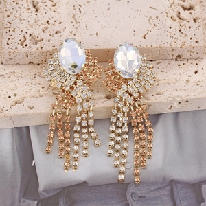 Macro view of long gold tassel earrings with oval crystal and sparkling glass rhinestones
