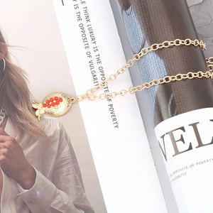Retro gold pomegranate pendant necklace with red beads on a stylish magazine background