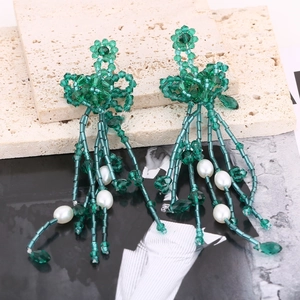 Detailed close-up of green crystal beaded tassel earrings with pearl floral accents