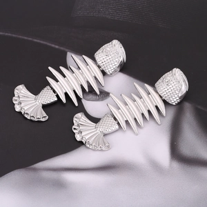 Macro detail of silver fishbone earrings with flexible articulated joints and sparkling eyes