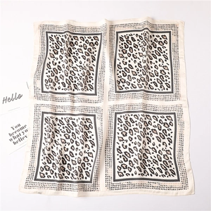 Detailed view of square silk scarf featuring symmetric leopard print on beige background