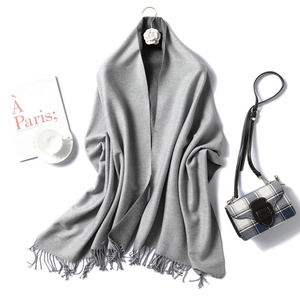 Detail of soft gray cashmere-style scarf with tassel trim and decorative flower hook